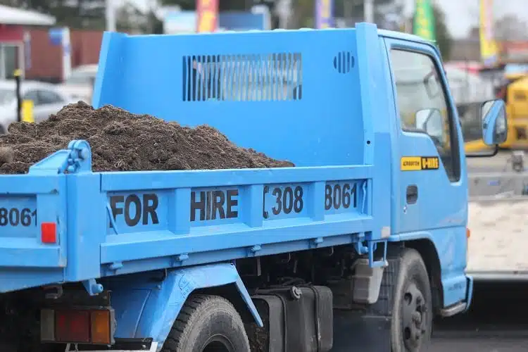 a blue tip truck with dirt in the back